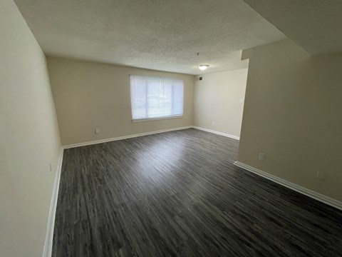 an empty living room with wood floors and a window