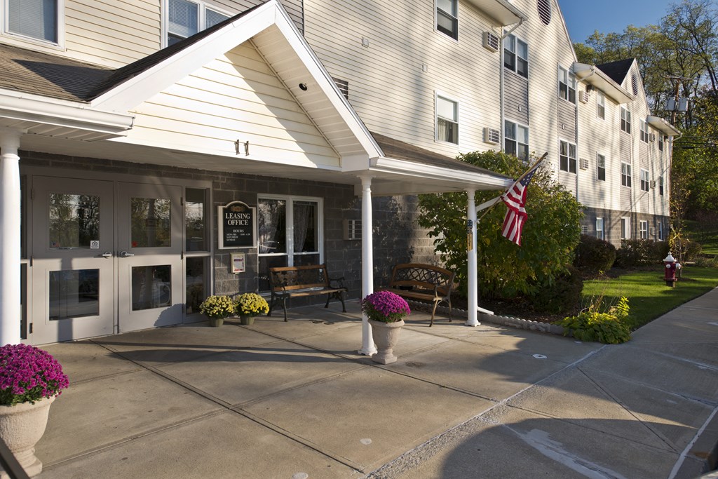 the front of a white building with a porch and an flag