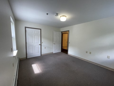 a bedroom with a carpeted floor and a door to a closet
