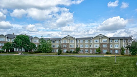 A large grassy field in front of apartment buildings.