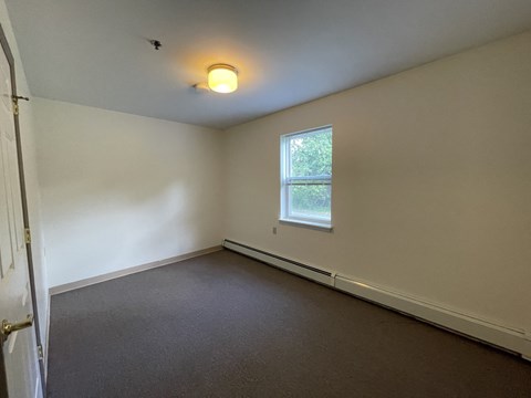 an empty room with a window and white walls