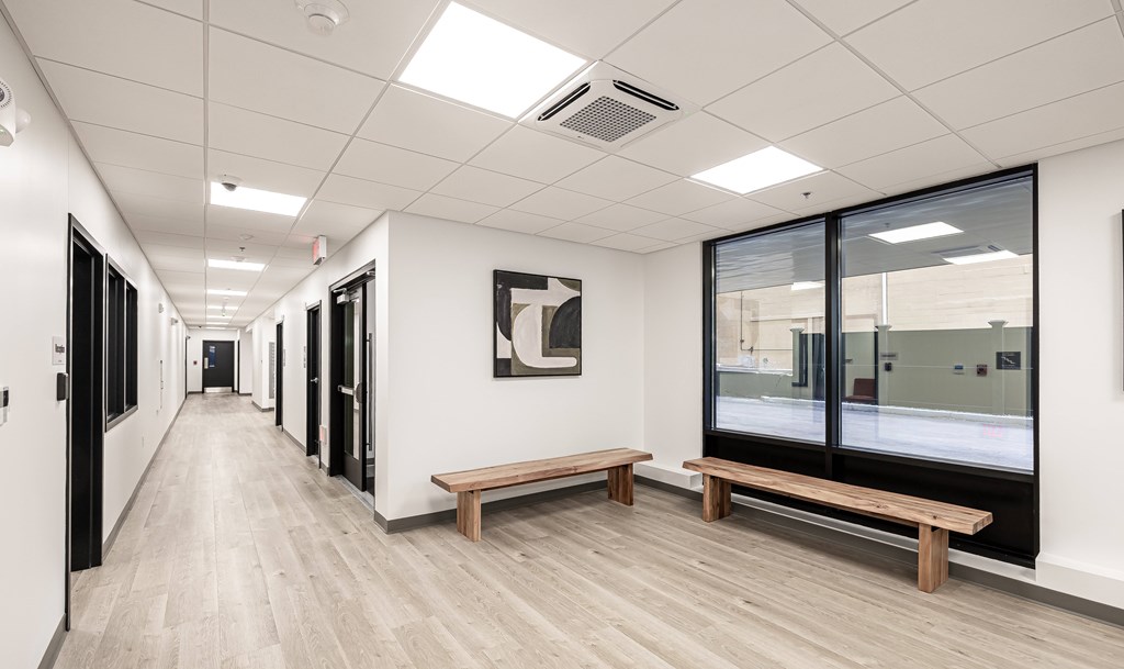A long hallway with a bench and a painting on the wall.