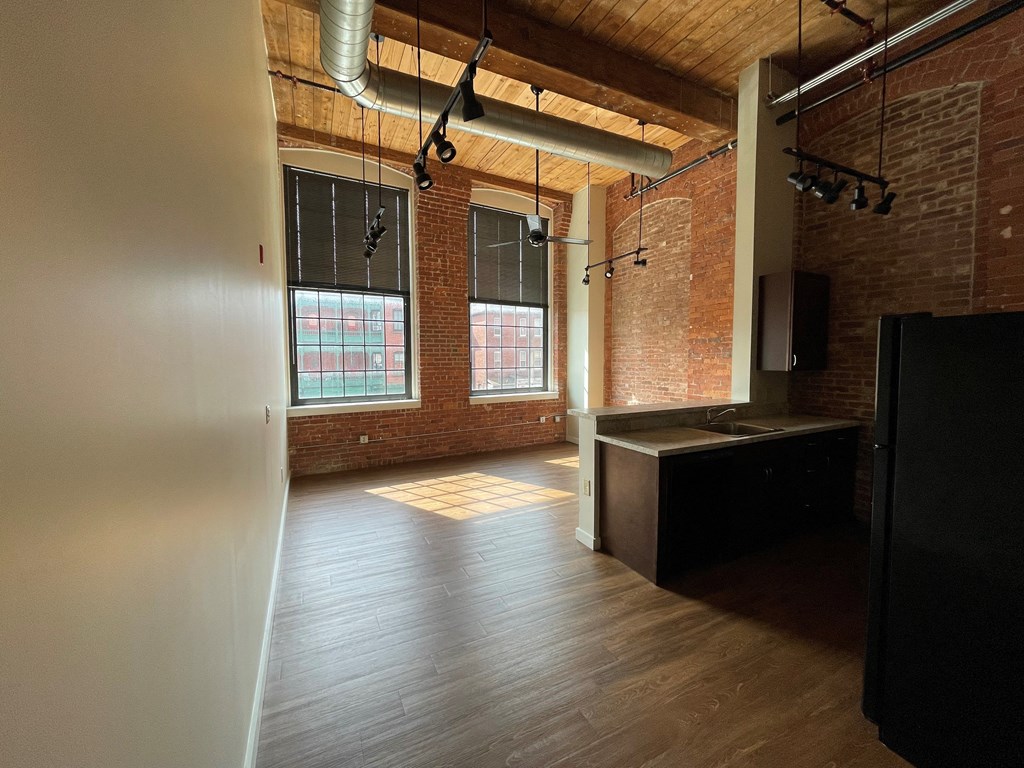an empty living room with brick walls and wood floors