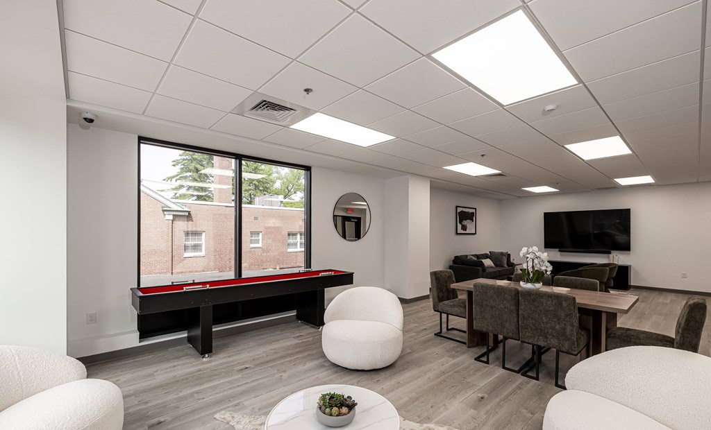 A living room with a white couch, a black table, and a window with a view of a building.