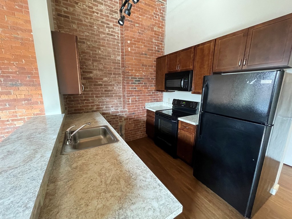 a kitchen with black appliances and a brick wall
