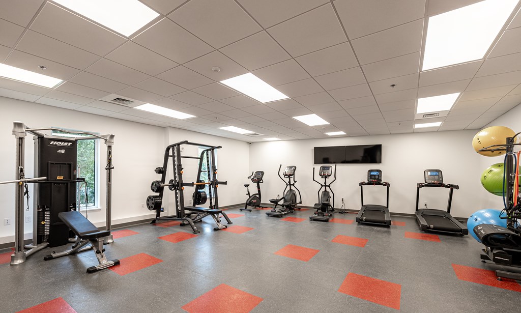 A gym with a variety of equipment including treadmills, weights, and exercise machines.