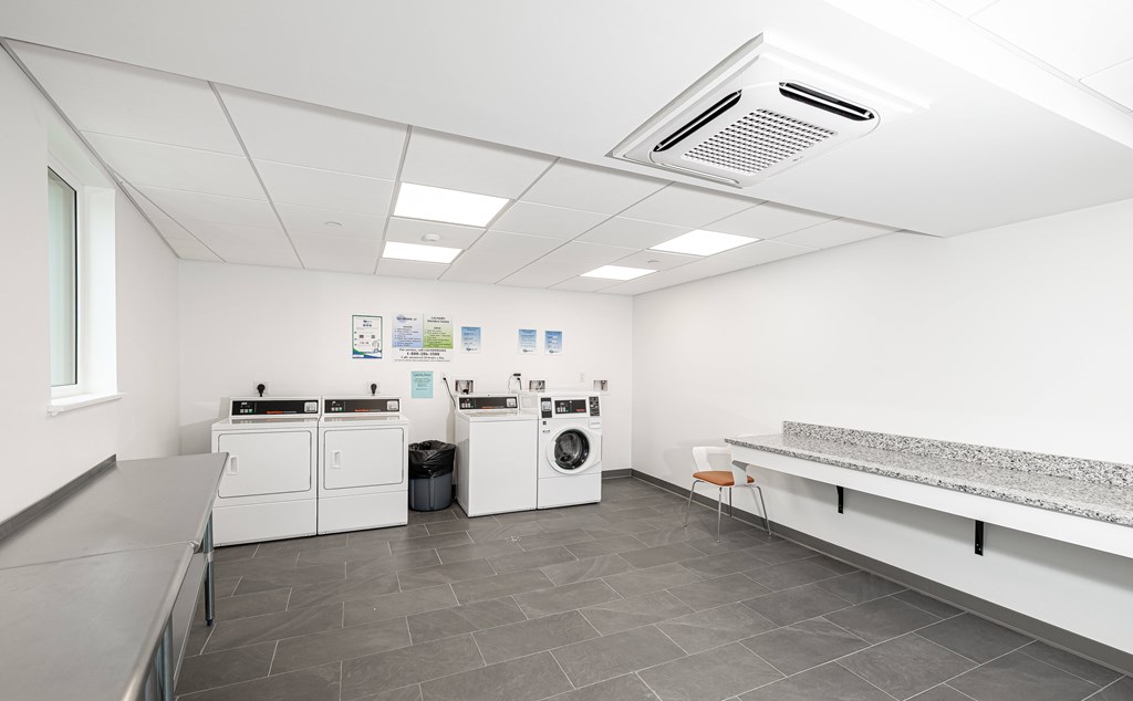 A laundry room with washers and dryers and a bench.