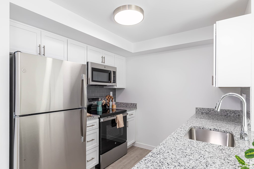 A kitchen with a stainless steel refrigerator, microwave, oven, and sink.
