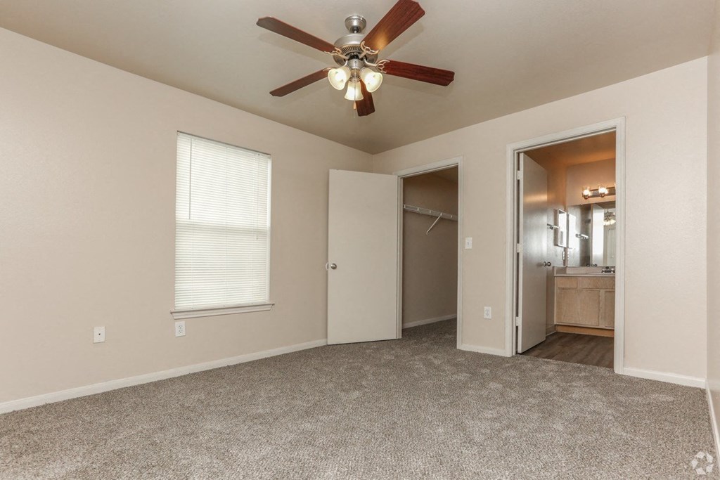 a bedroom with a ceiling fan and a door to a bathroom