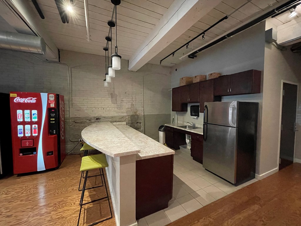 a kitchen with a counter and a refrigerator and a soda machine