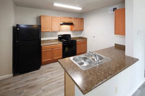 A kitchen with black appliances and wooden cabinets.