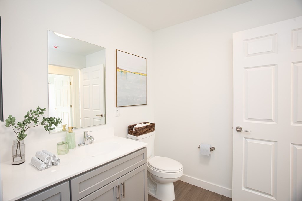 A white bathroom with a toilet, sink, and mirror.