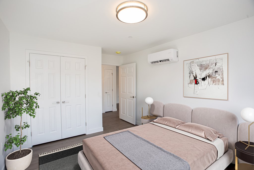 A bedroom with a bed, a potted plant, and a painting on the wall.