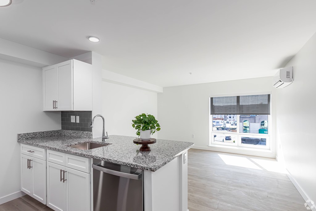 A kitchen with white cabinets and a granite countertop.