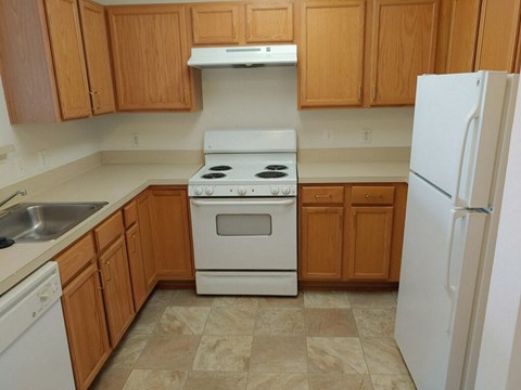 A kitchen with wooden cabinets and a white stove top oven.
