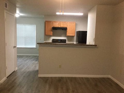 A kitchen with wooden cabinets and a black refrigerator.