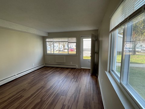 an empty living room with wood flooring and large windows