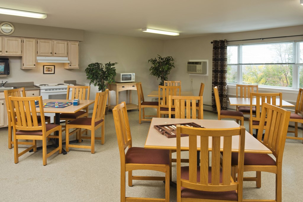 a dining room with tables and chairs and a kitchen
