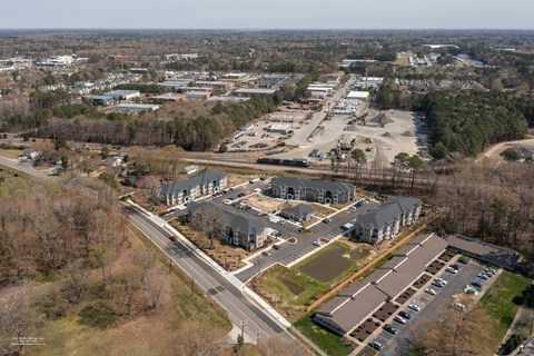 An aerial view of a parking lot and buildings with trees in the background.