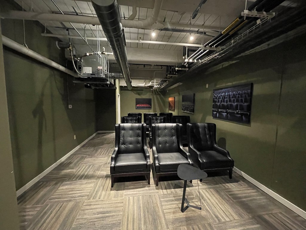 a room with leather chairs and a green wall and a projector
