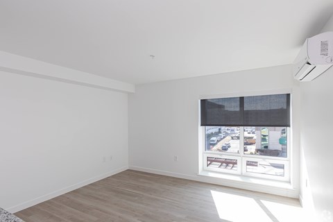 A room with a window showing a view of a street with cars and buildings.