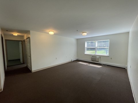 an empty living room with white walls and a window