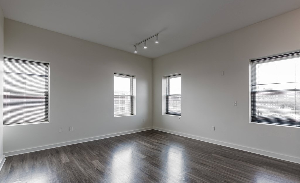 an empty living room with wood floors and two windows