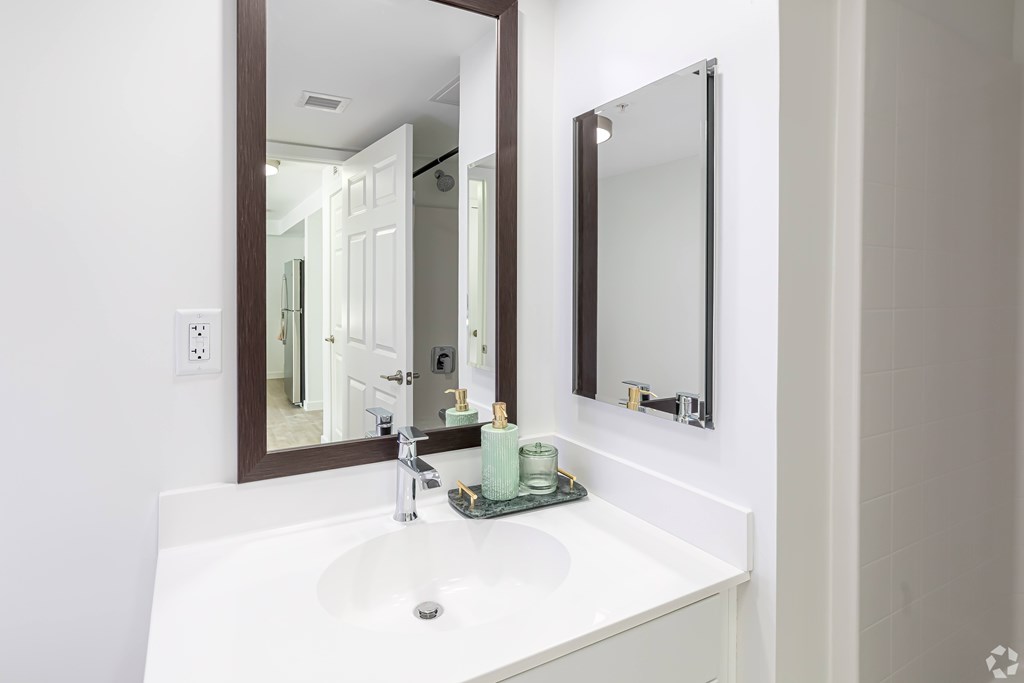 A white sink with a silver faucet and a brown mirror above it.