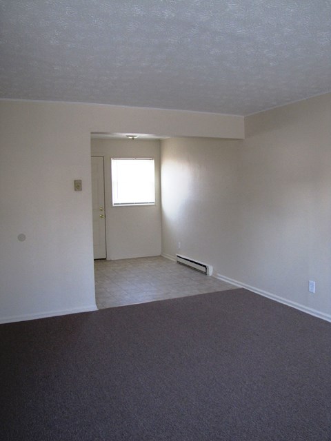 an empty living room with white walls and a window