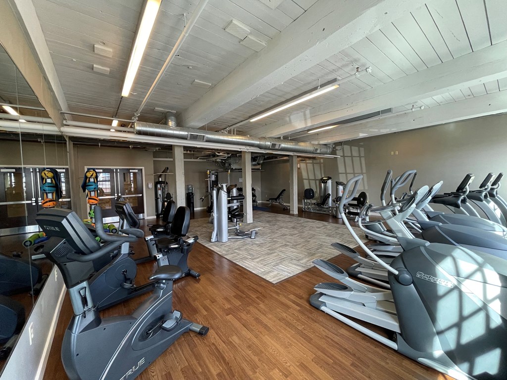 a gym with cardio machines and weights on a wood floor