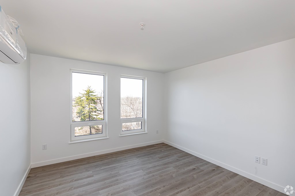 A room with a window and a wooden floor.