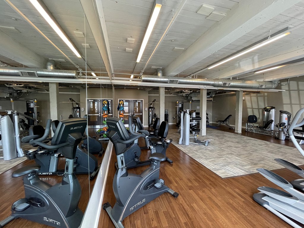 a gym with cardio machines and weights on a wooden floor