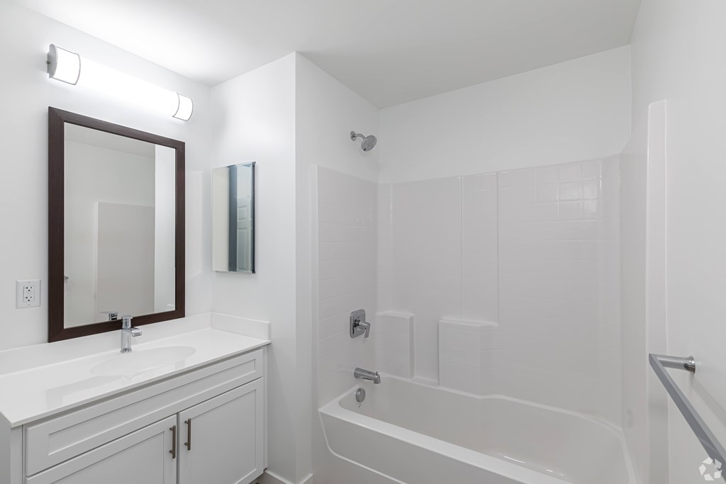 A white bathroom with a white tub and a white sink.
