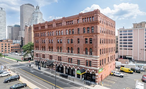 A red brick building with a green awning sits on a street corner.