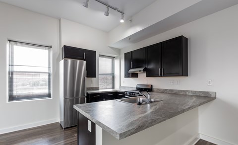 A modern kitchen with a stainless steel refrigerator and black cabinets.