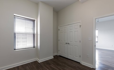 A room with a white door and a window with blinds.