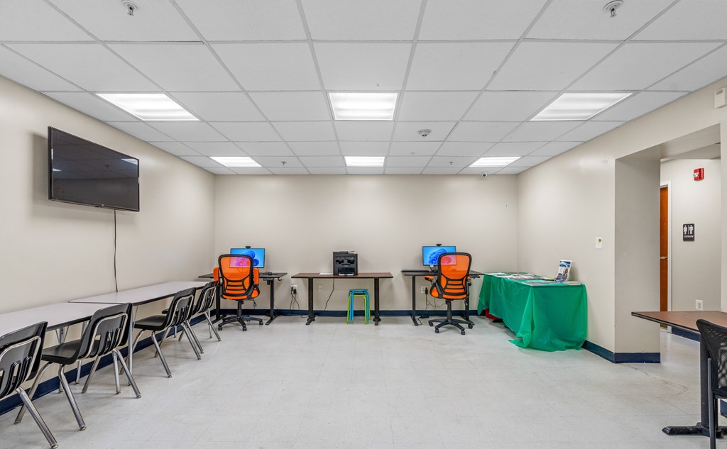 A conference room with a long table, chairs, and a television mounted on the wall.