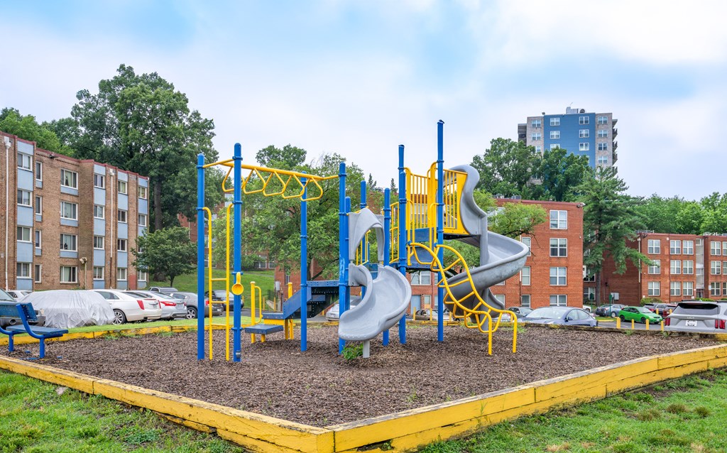 A playground with a yellow and blue slide and a yellow and blue climbing frame.