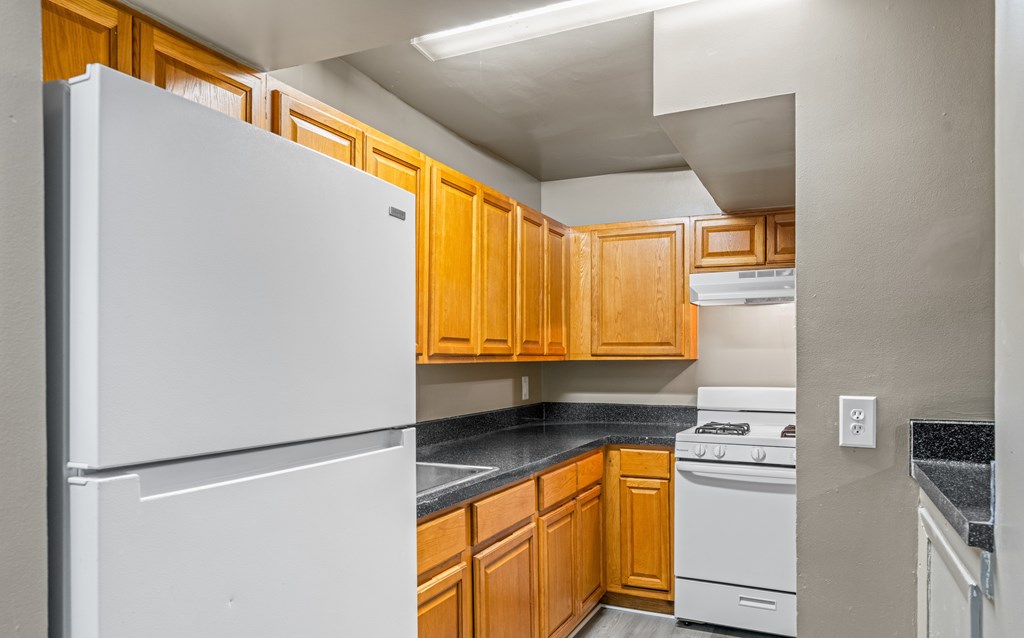 A kitchen with a white refrigerator and wooden cabinets.