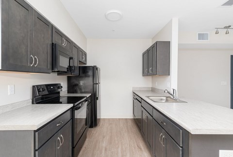 A kitchen with black cabinets and white countertops.