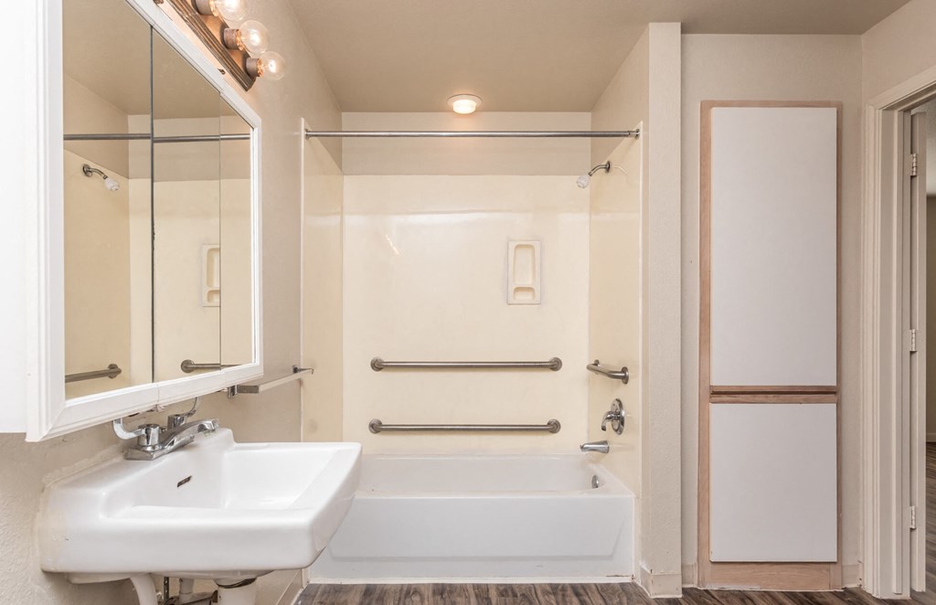 a white bathroom with a tub and sink and a mirror
