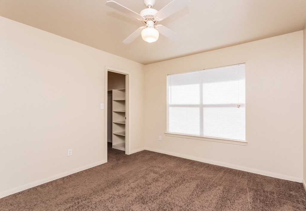 the spacious living room with carpet and a ceiling fan