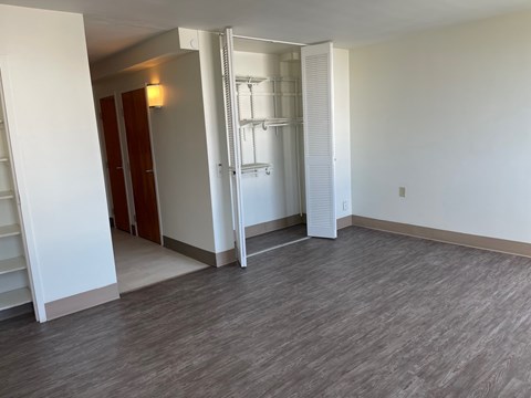A room with a white wall and a grey floor with a white door.