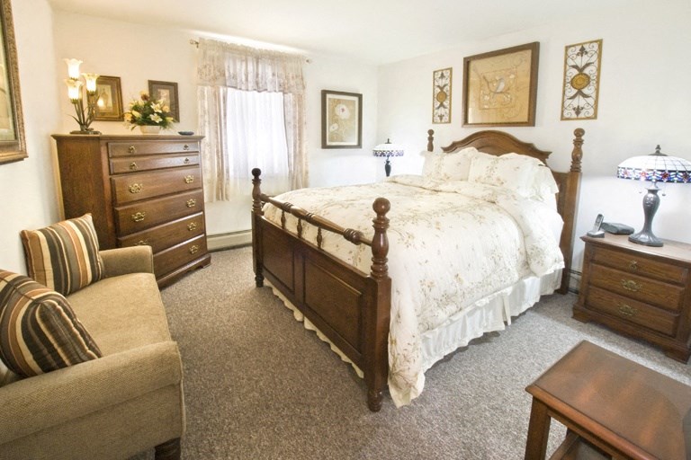 a bedroom with a bed and a chair and a dresser