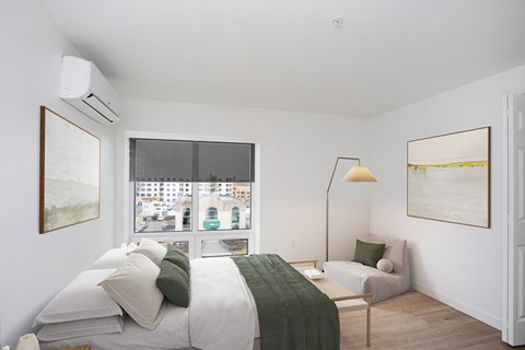 A bedroom with a bed, a couch, and a window with a view of the city.