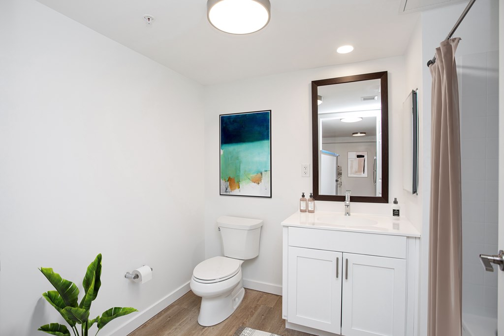 A white bathroom with a toilet, sink, and a mirror.