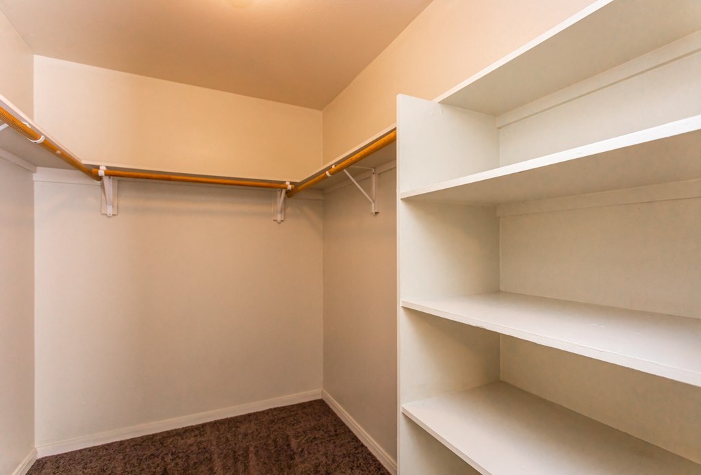 a walk in closet with white shelves and