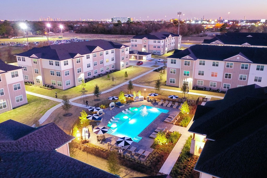 an aerial view of a resort style swimming pool at night at 55 Fifty at Northwest Crossing, Texas