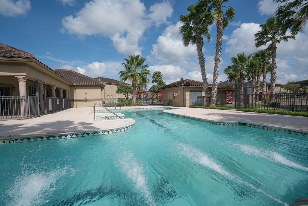 a large swimming pool with palm trees in front of a house