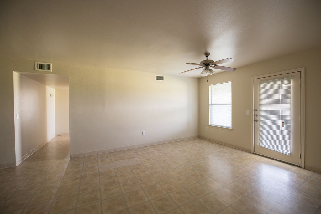an empty living room with a ceiling fan and a window